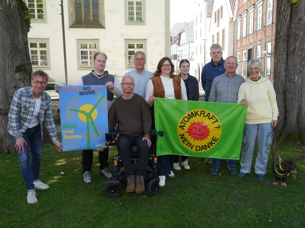 Gruppenbild von Vorstandsmitgliedern der GRÜNEN im Kreis Höxter mit historischem Plakat "No more Tschernobyls. Wind und Sonne statt Atom" Und einer grünen Fahne "Atomkraft? Nein danke!"